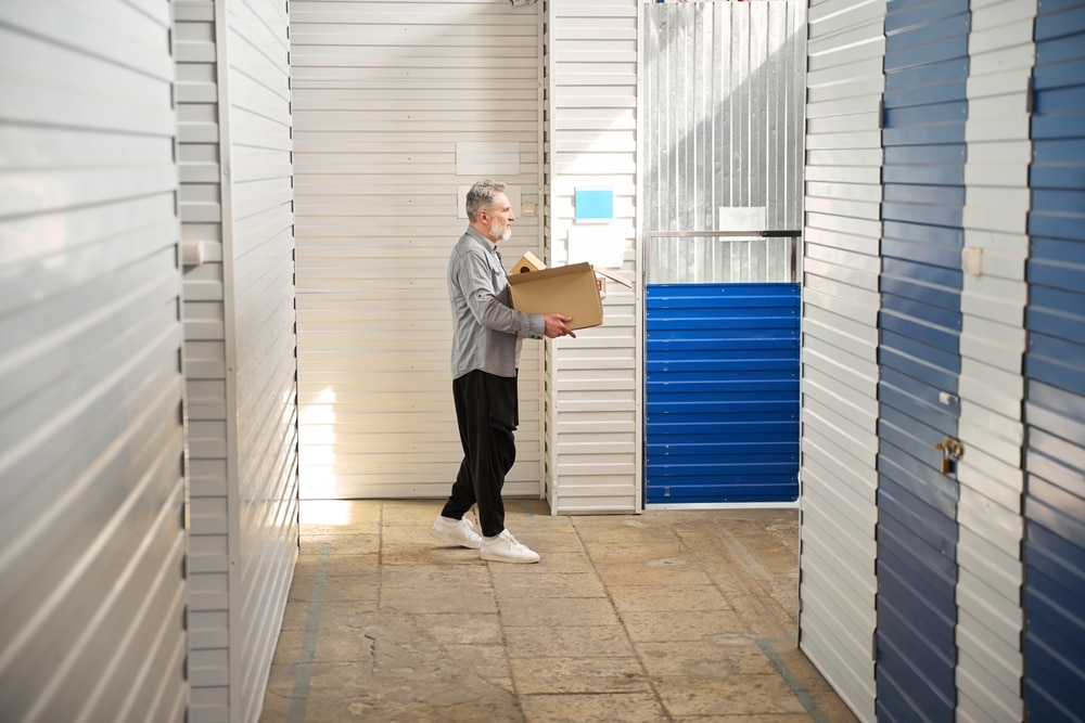 Man,Walking,With,Box,,Working,In,Storage,Unit